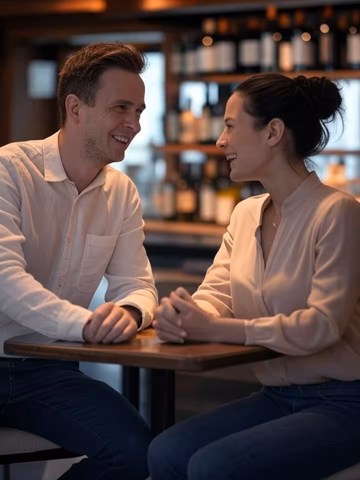 two people engaged in animated conversation at modern wine bar, body language showing genuine intell