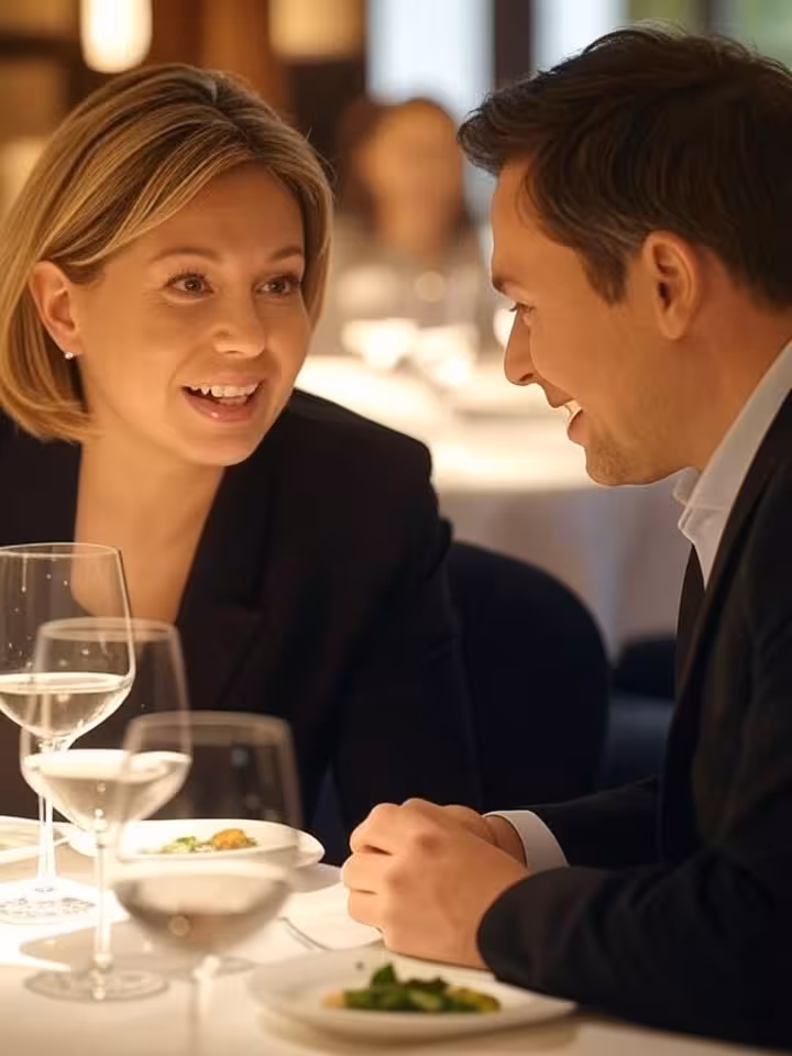 Two people having animated conversation at restaurant table, body language showing engagement and re